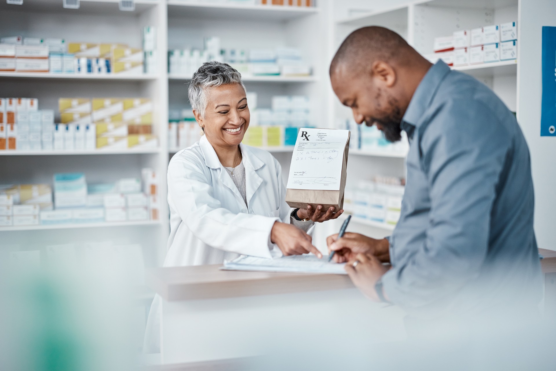 Medicine, shopping or pharmacist with customer writing personal or medical information in pharmacy. Consulting, pills or happy senior doctor helping or speaking to black man or sick African customer