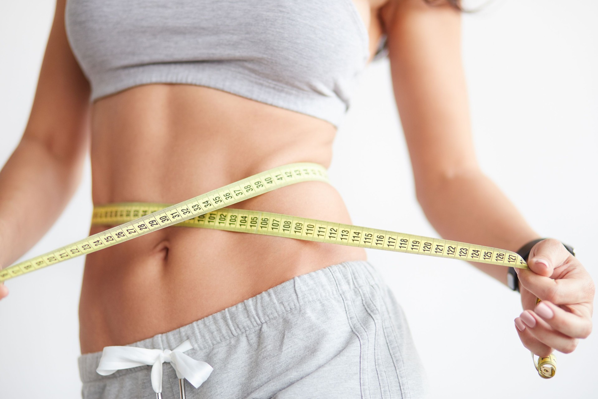 Slim girl with centimeter on white